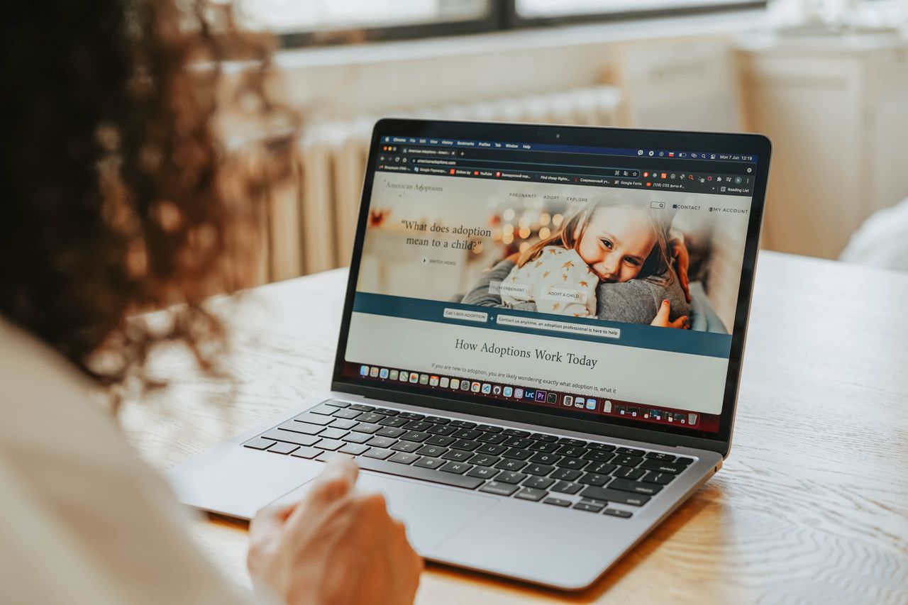 Une femme consulte des informations sur l’adoption sur un ordinateur portable, à l’intérieur.